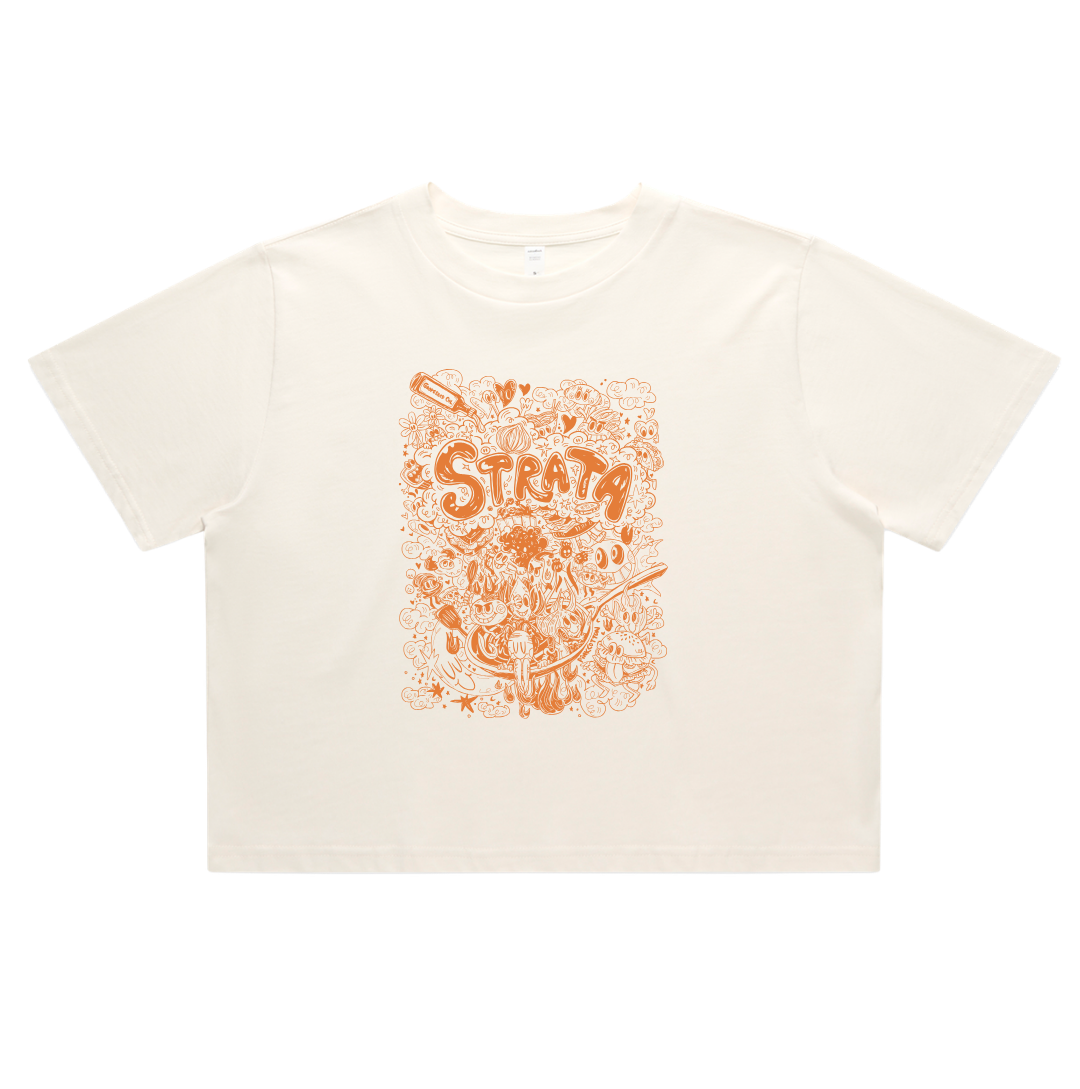 An off-white short-sleeve crop top t-shirt featuring a prominent orange graphic print on the front with the word 'STRATA' and dreamy doodles, displayed flat against a white background.