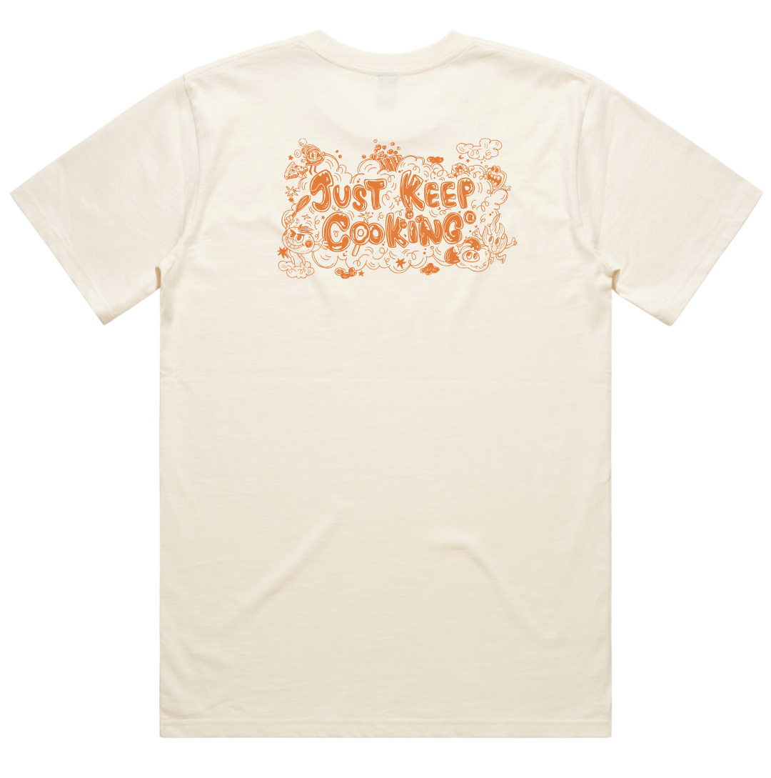 An off-white short-sleeve t-shirt with a retro-style orange graphic on the back reading 'Just Keep Cooking' surrounded by hand-drawn doodles, shown against a plain white background.