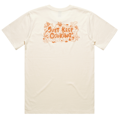 An off-white short-sleeve t-shirt with a retro-style orange graphic on the back reading 'Just Keep Cooking' surrounded by hand-drawn doodles, shown against a plain white background.